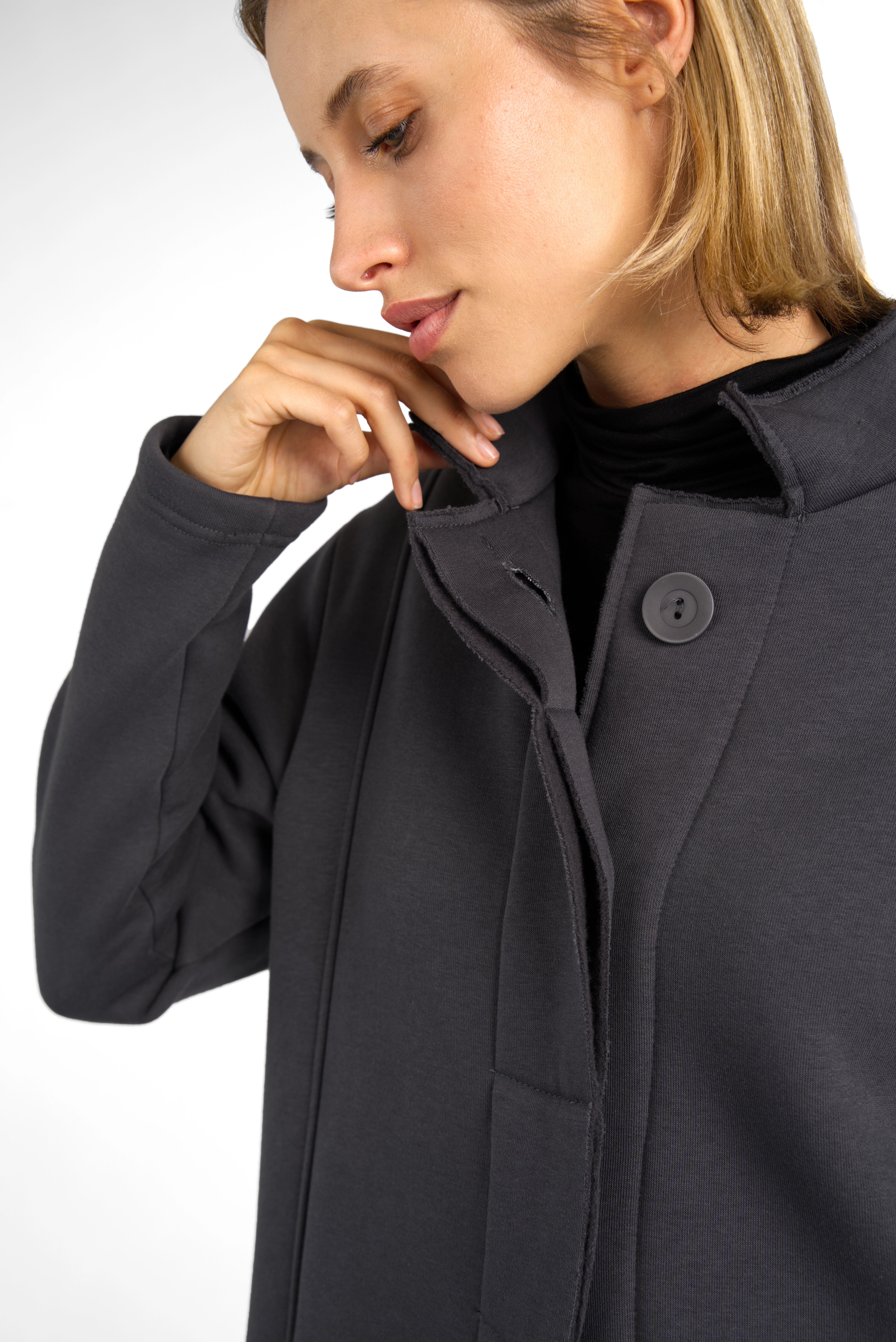 Close-up of a woman wearing a dark grey MANEY Sweatmantel with a concealed button placket and brushed jersey fabric for comfort.