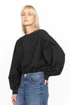 Woman wearing black MILLIE Crinkle Bluse with sculptural balloon sleeves and elastic waistband paired with blue jeans