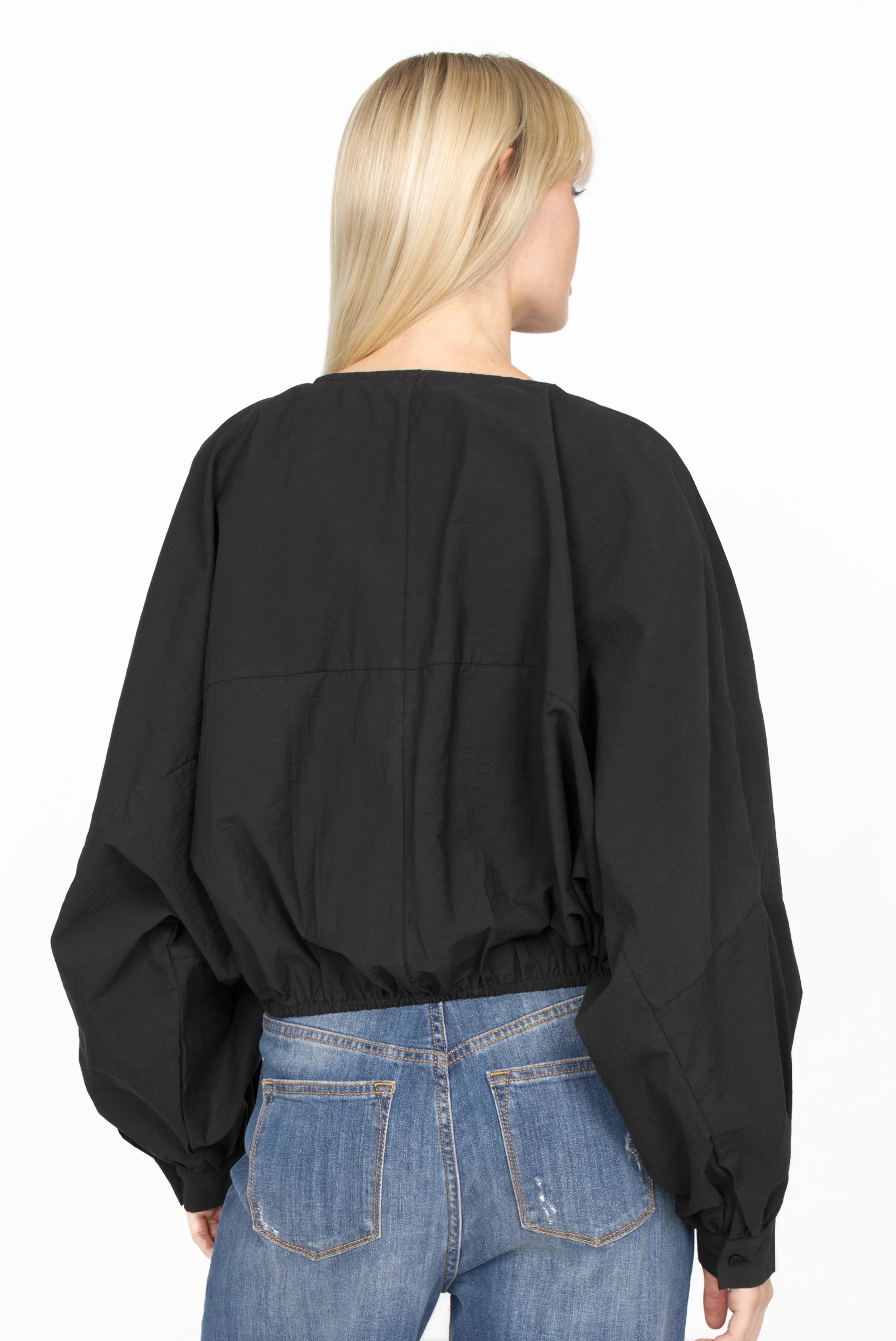 Back view of a model wearing a black MILLIE Crinkle Bluse with balloon sleeves and elastic waistband