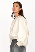 Woman wearing a white MILLIE Crinkle Bluse with balloon sleeves and elastic waistband