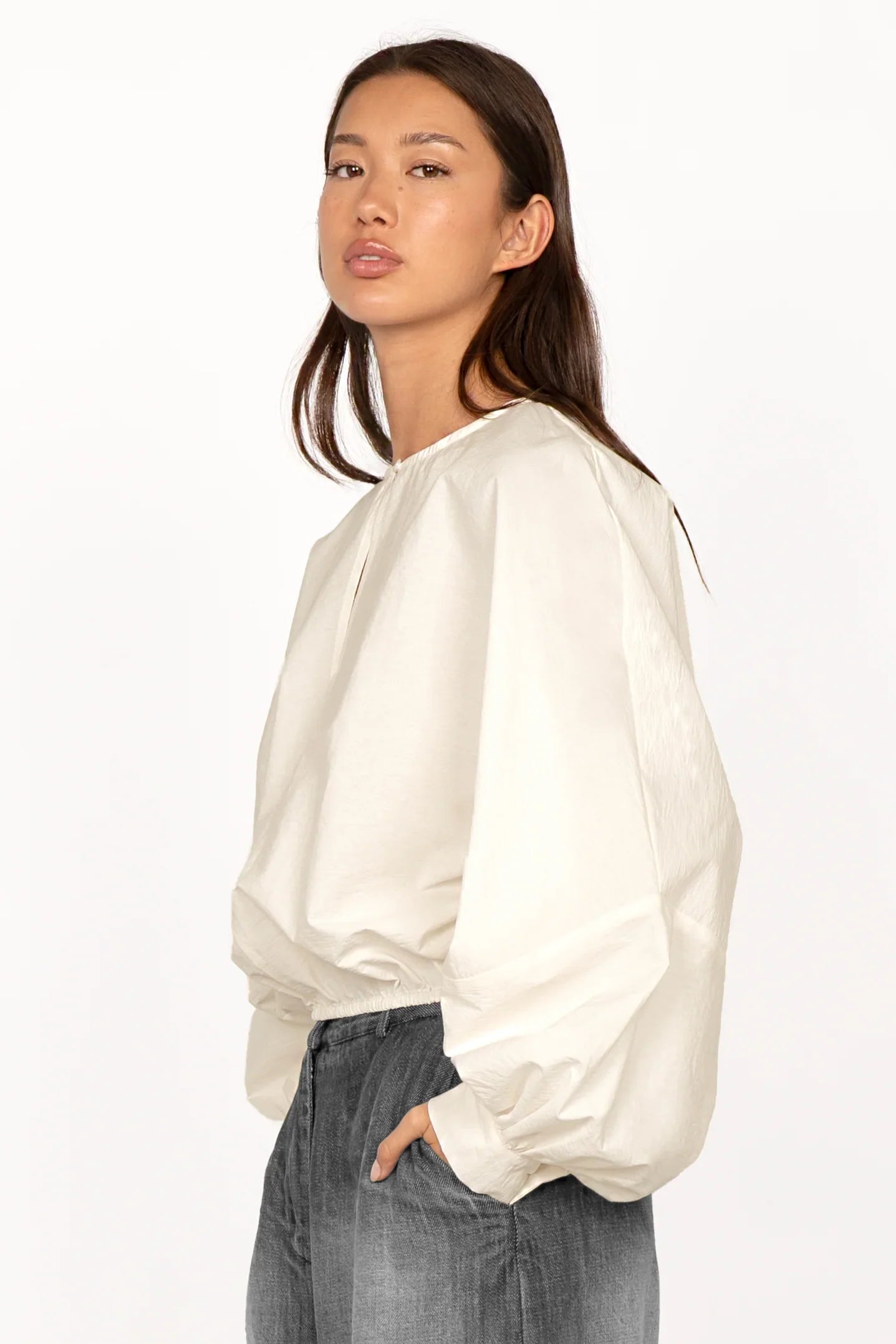 Woman wearing a white MILLIE Crinkle Bluse with balloon sleeves and elastic waistband