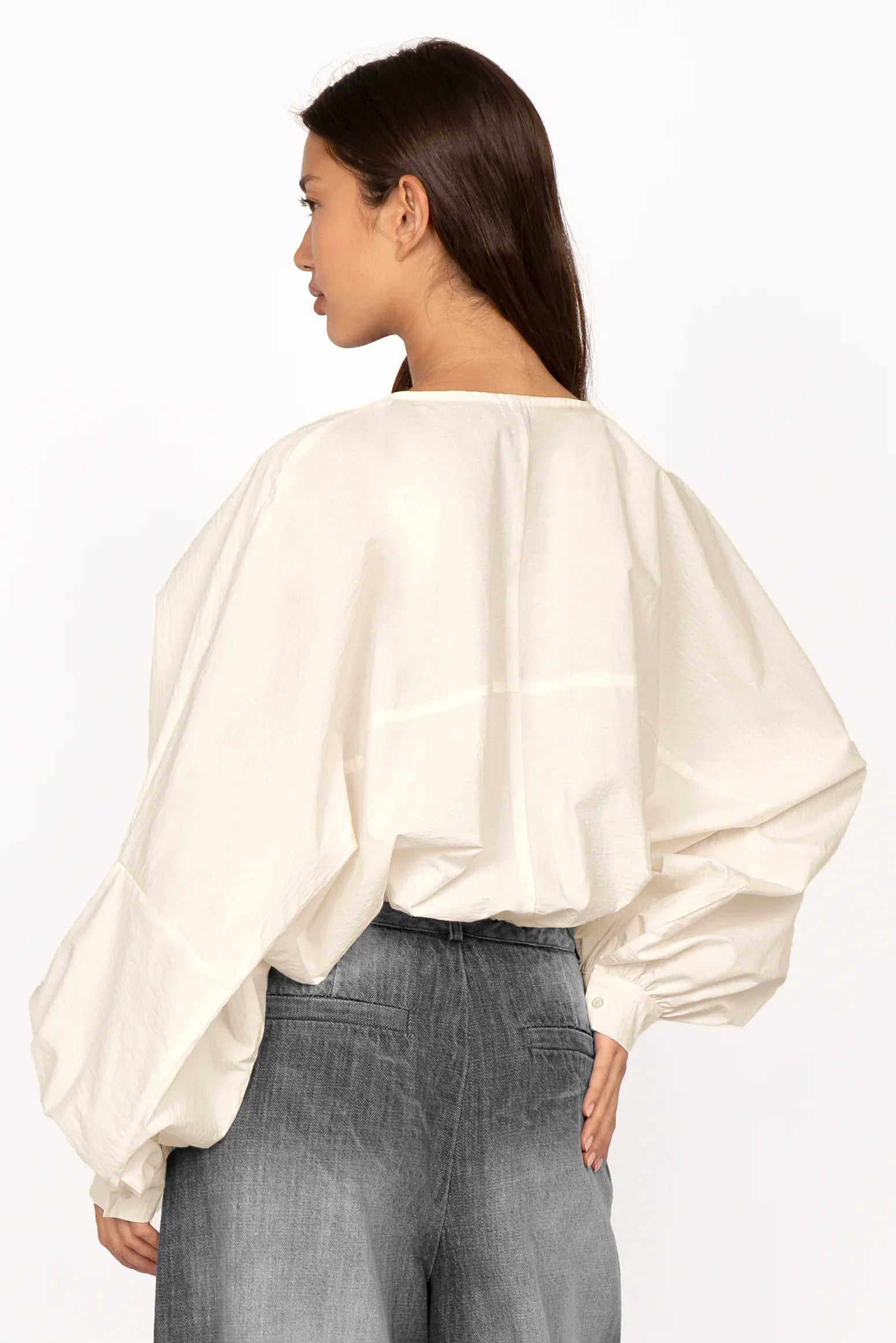 Back view of a woman wearing a white MILLIE Crinkle Bluse with loose fit and sculptural balloon sleeves.