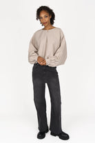 Woman wearing a beige loose fit MILLIE Crinkle Bluse with balloon sleeves and elastic hem paired with black wide-leg jeans and black boots