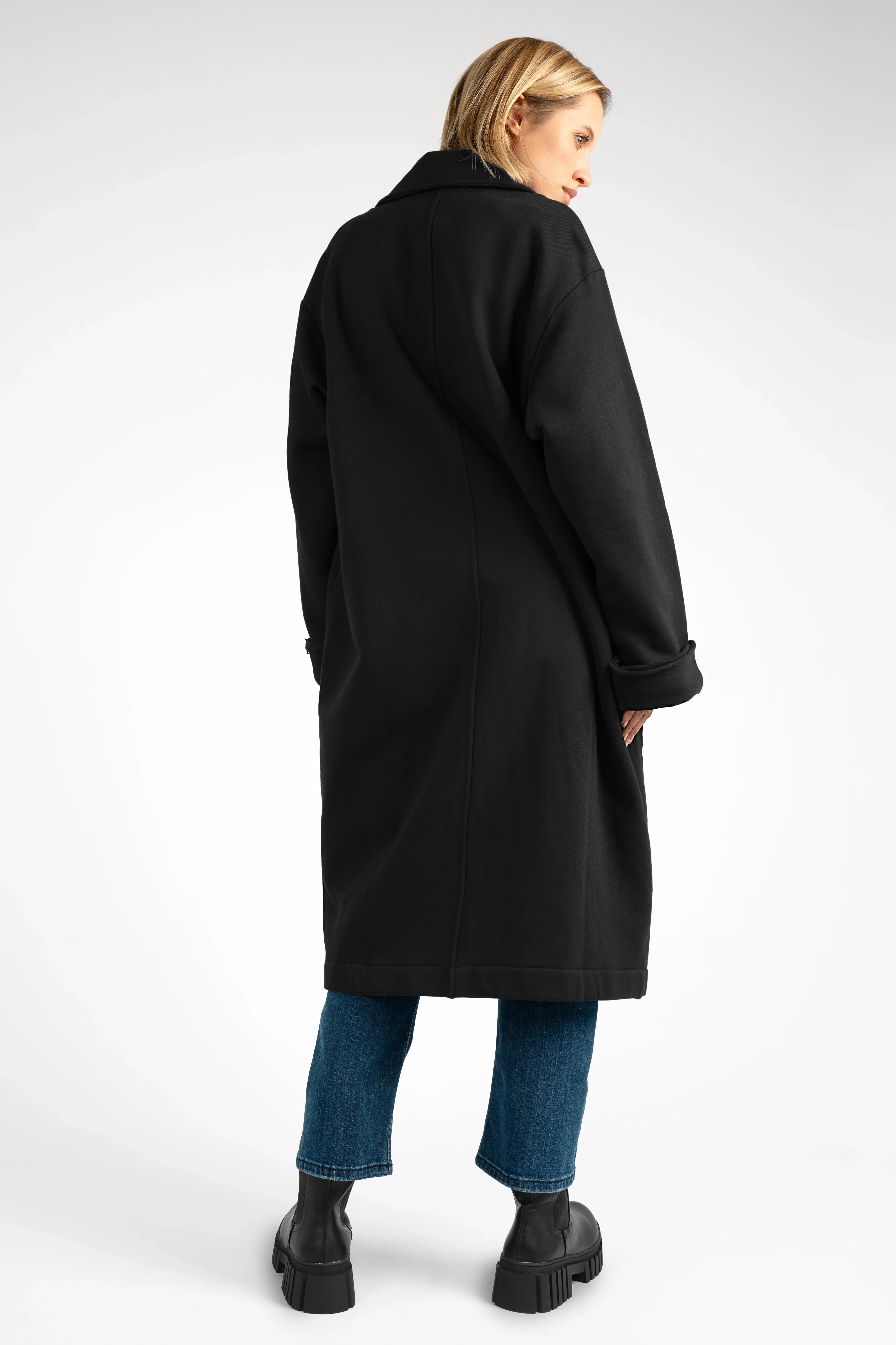 Woman wearing black MONDY.K Oversize Sweatmantel with large pockets and rolled-up sleeves.