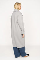 Frau trägt MONDY.K Oversize Sweatmantel in Grau mit Reverskragen und großen Taschen, seitliche Ansicht.