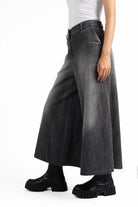 NEDITA Cropped Wide Leg Hose in washed black soft cotton with mid waist and wide cropped legs, styled with black chunky boots.