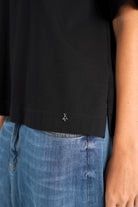 schwarzes NITI.K Shirt aus elastischem Baumwolljersey mit kastiger Passform und seitlichen Schlitzen, kombiniert mit blauer Jeans