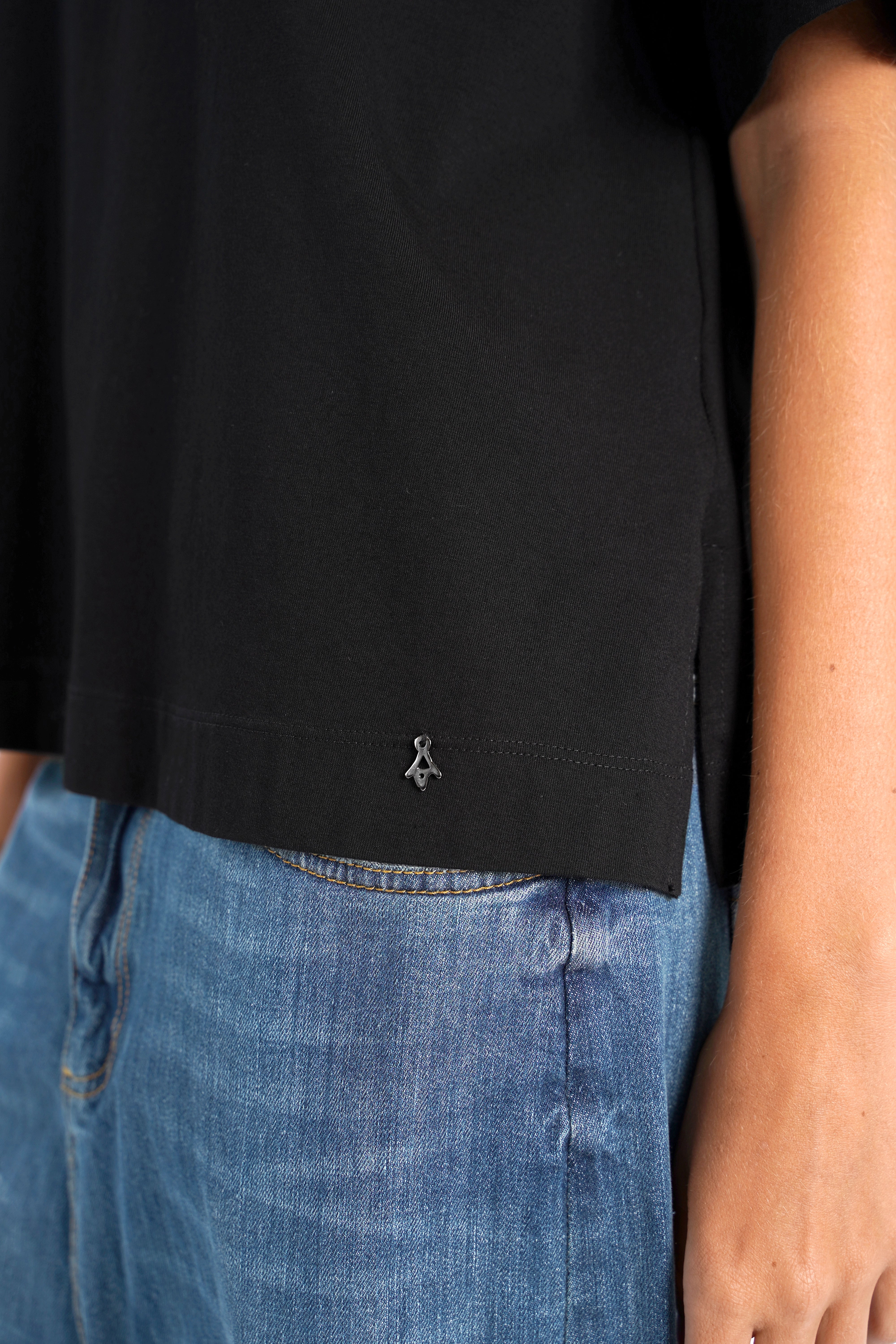 schwarzes NITI.K Shirt aus elastischem Baumwolljersey mit kastiger Passform und seitlichen Schlitzen, kombiniert mit blauer Jeans