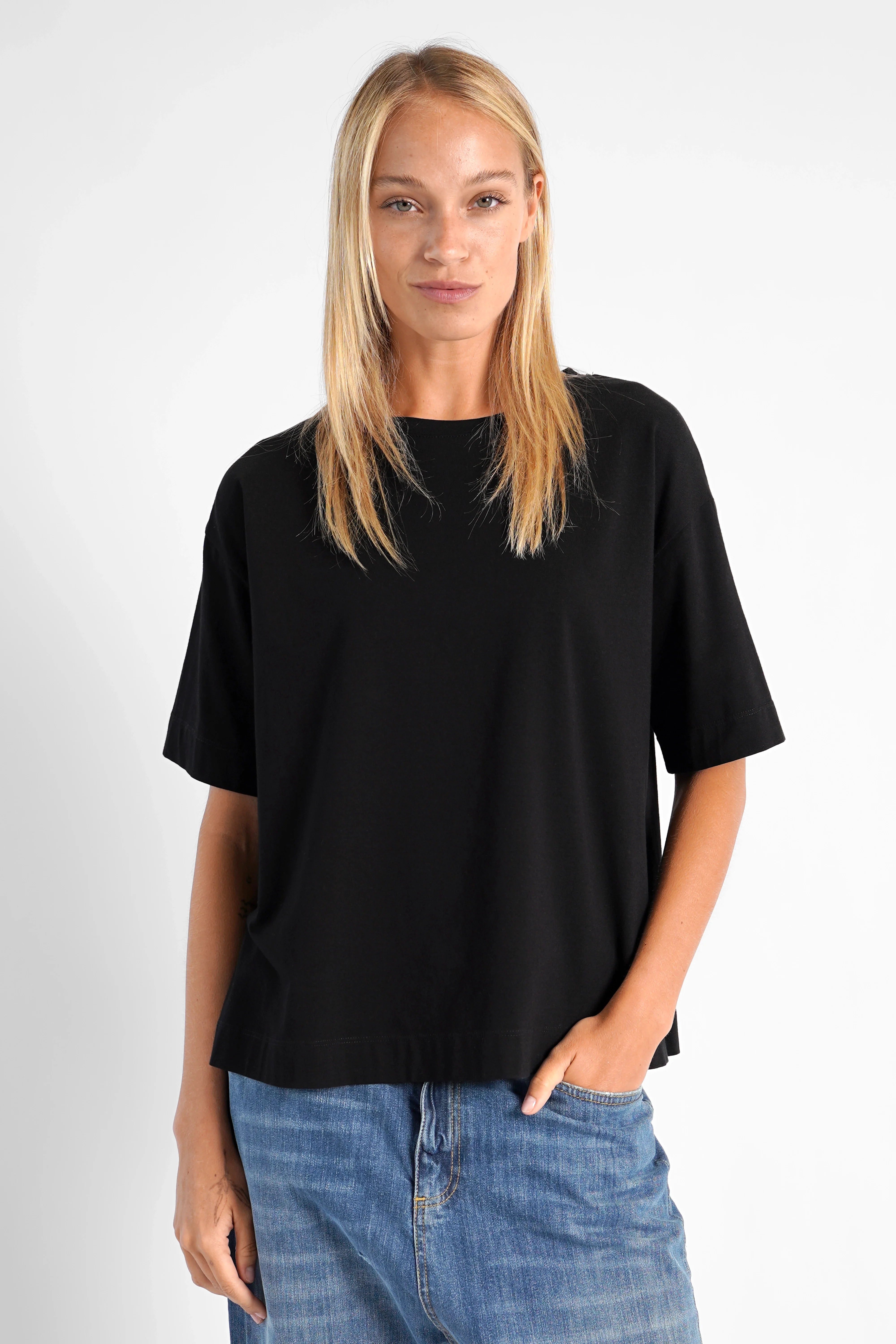 Schwarzes NITI.K Shirt aus elastischem Baumwolljersey mit Rundhalsausschnitt, kastiger Passform und seitlichen Schlitzen, getragen von Frau