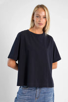 Damen trägt schwarzes NITI.K Shirt aus Baumwolle mit kastiger Passform, Rundhalsausschnitt und seitlichen Schlitzen