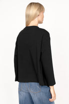 Frau trägt NITI.K Langarm Shirt aus elastischem Baumwolljersey in Schwarz mit relaxed Fit und überschnittenen Schultern von hinten.