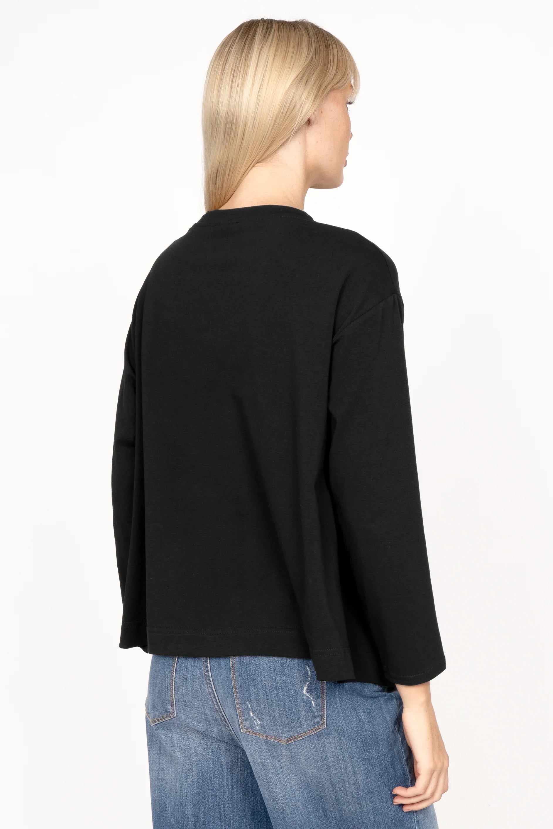 Frau trägt NITI.K Langarm Shirt aus elastischem Baumwolljersey in Schwarz mit relaxed Fit und überschnittenen Schultern von hinten.