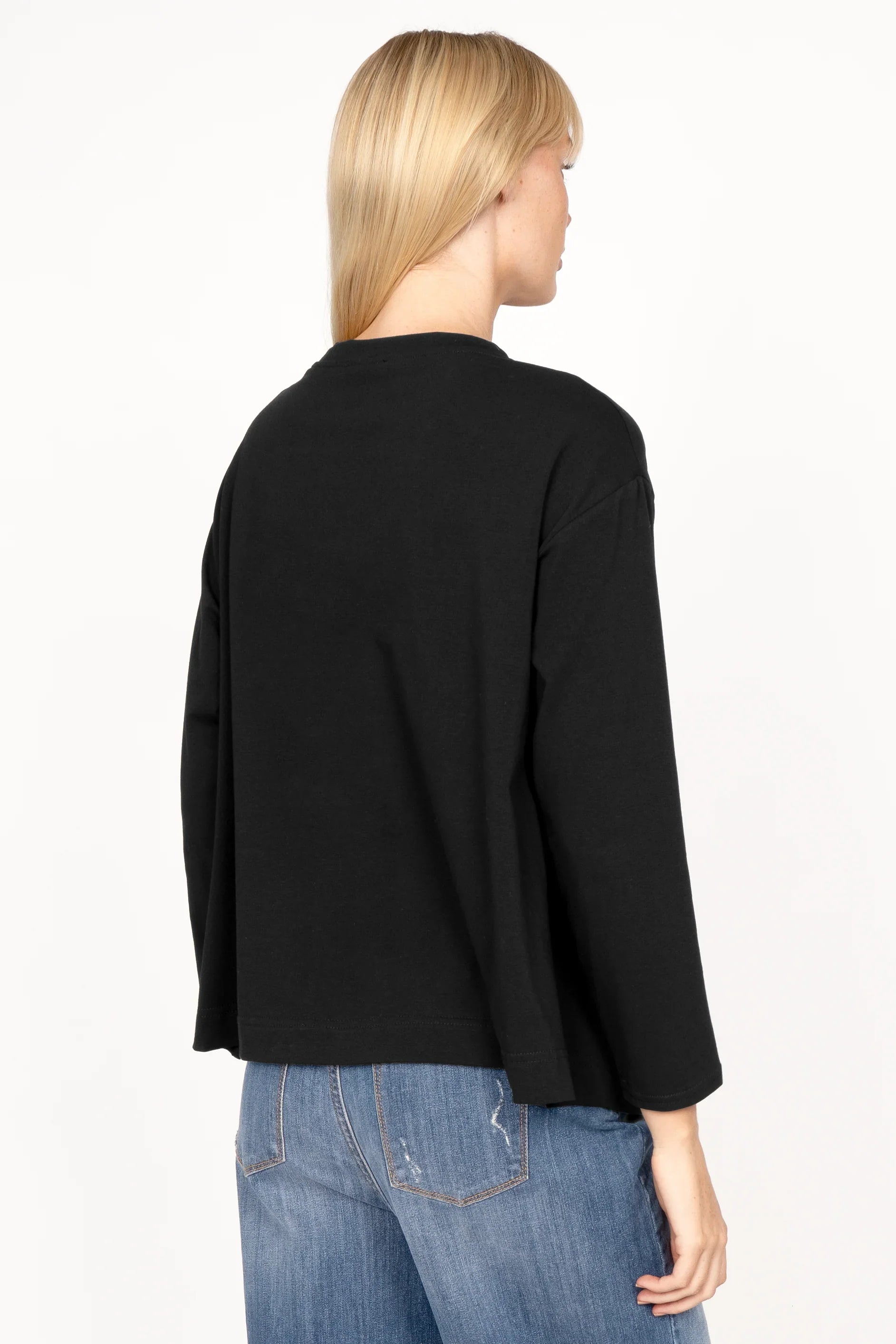 Back view of a woman wearing black NITI.K Langarm Shirt with long sleeves and relaxed fit paired with blue jeans