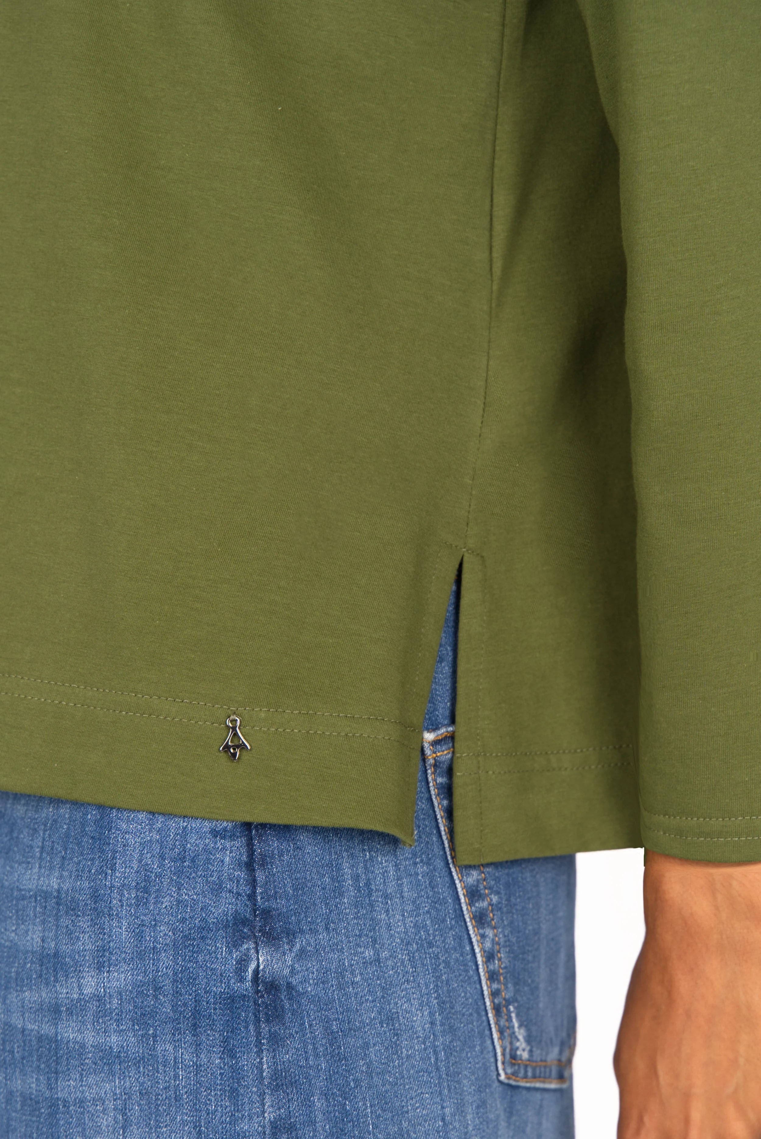 Close-up of olive green NITI.K Langarm Shirt with side slit detail and relaxed fit on model wearing blue jeans