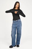 Woman wearing black NJELI Longsleeve with round neckline, extra-long sleeves with thumb holes, and slim fit paired with blue jeans