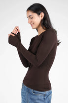 Woman wearing brown NJELI Longsleeve with round neckline and thumb holes in extra long sleeves.