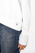 OSASU Cropped Longsleeve weiß mit weitem Rundhalsausschnitt und geschnittenen Kanten, kombiniert zu blauen Jeans