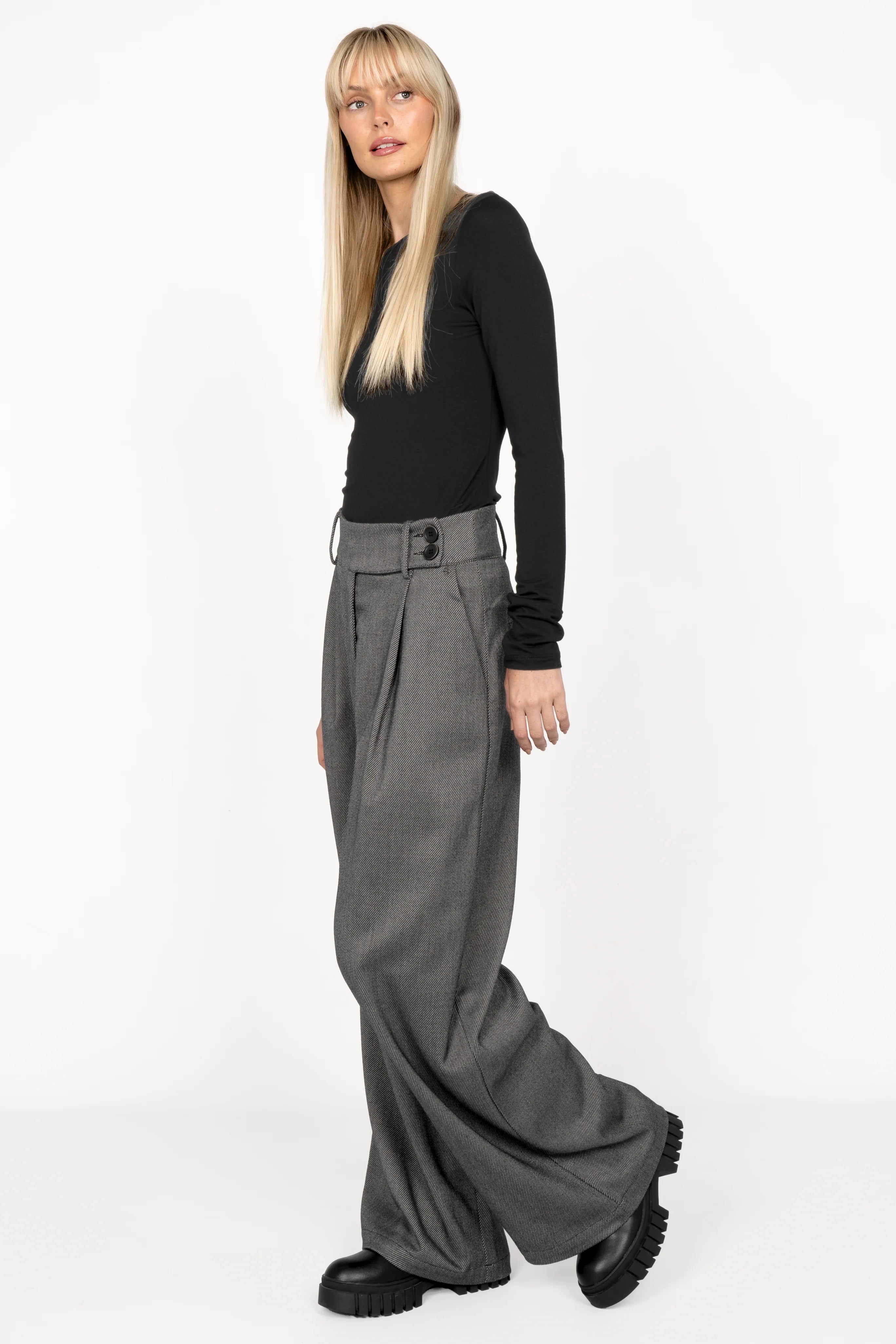 Woman wearing RYONI Marlene-Hose high waist wide leg gray trousers with asymmetric buttoned waistband and black top.
