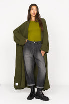 SAIKA Relaxed Tapered Hose in denim look with gradient wash and relaxed fit, styled with green knit cardigan and boots.