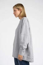 Woman wearing a relaxed fit gray SELKA Sweater with raglan sleeves and a slightly longer back hem