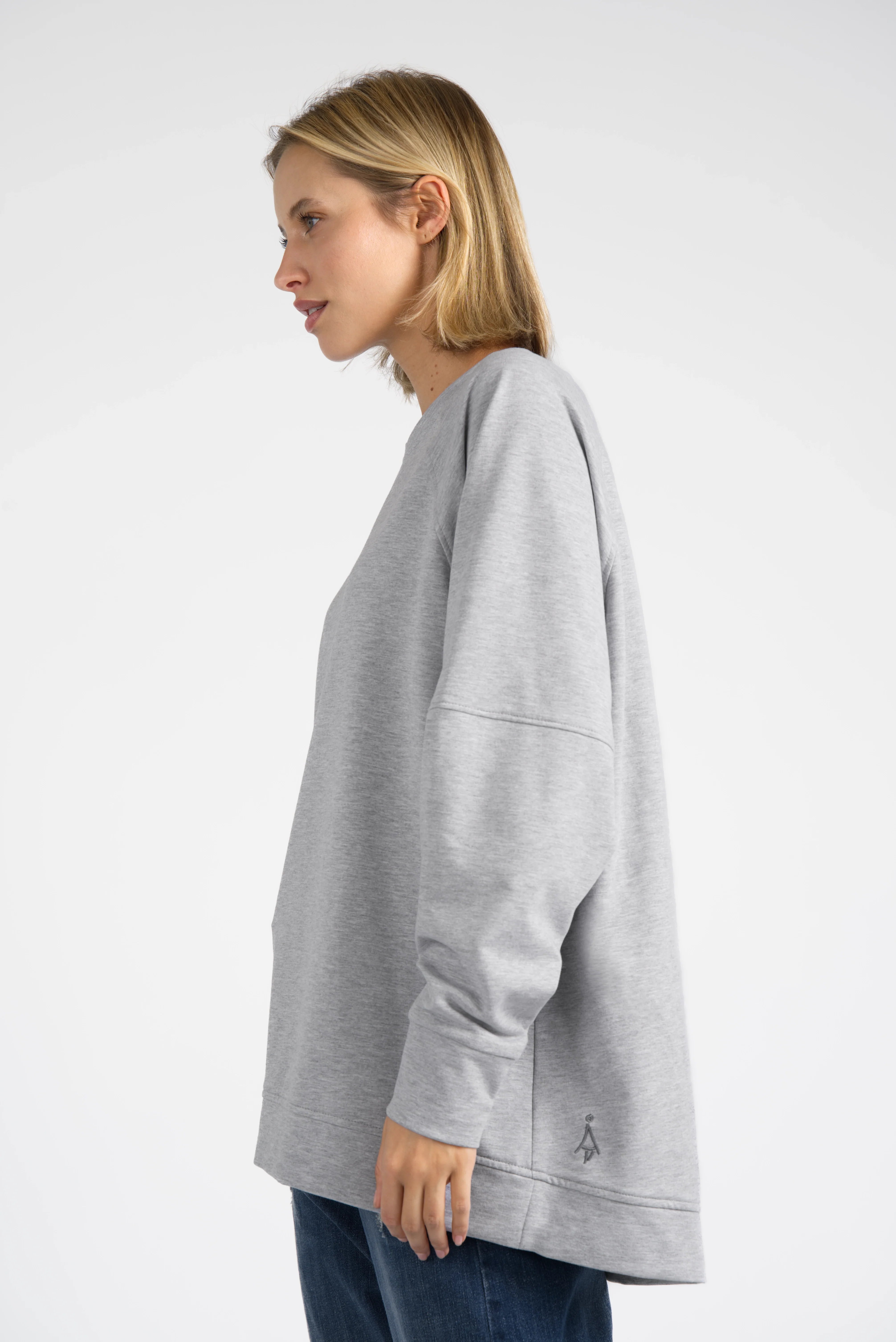 Woman wearing a relaxed fit gray SELKA Sweater with raglan sleeves and a slightly longer back hem