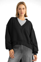 Woman wearing black SEREA Sweater mit V-Ausschnitt with deep V-neck, cropped hem, and gathered sleeve detail.