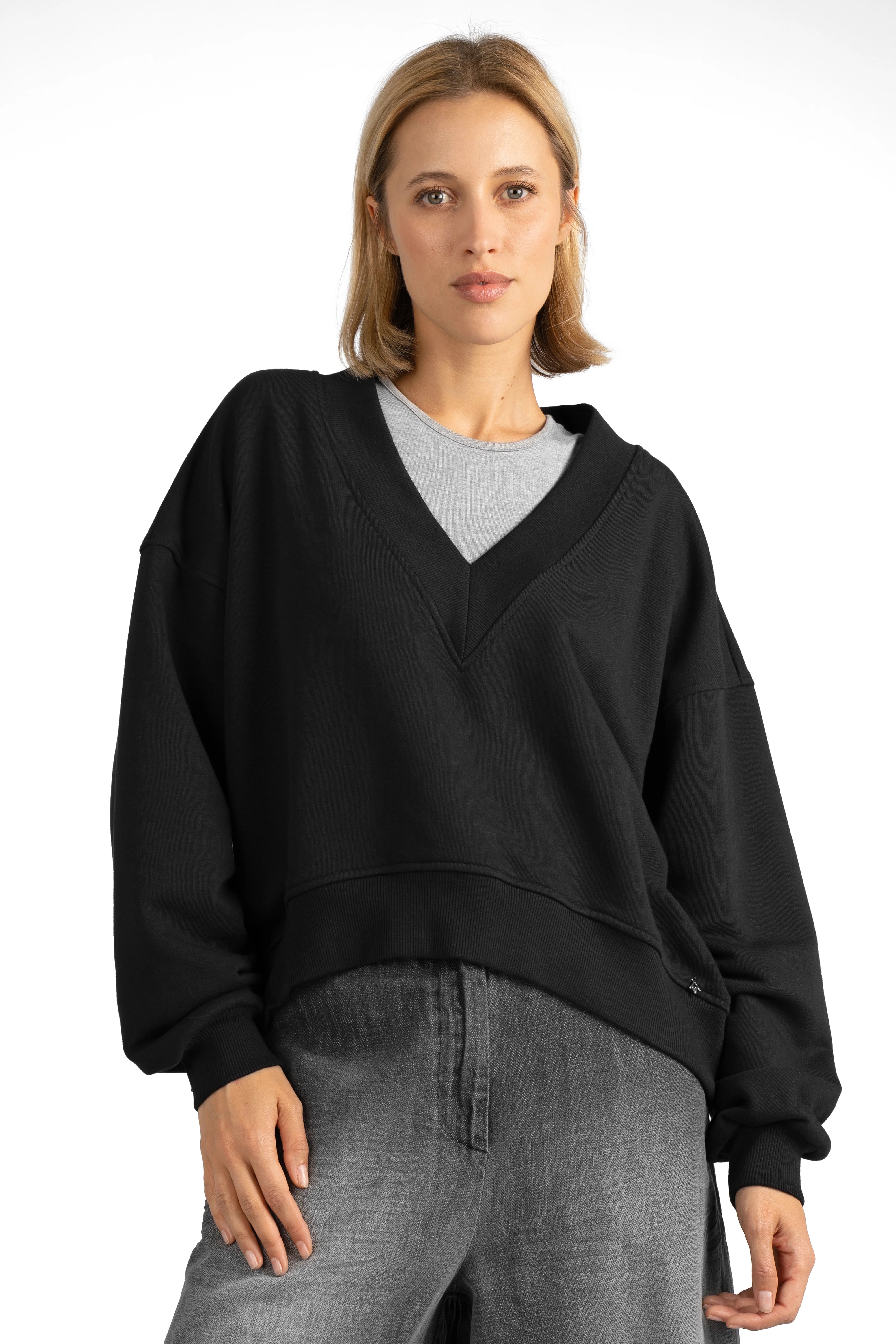 Woman wearing black SEREA Sweater mit V-Ausschnitt with deep V-neck, cropped hem, and gathered sleeve detail.