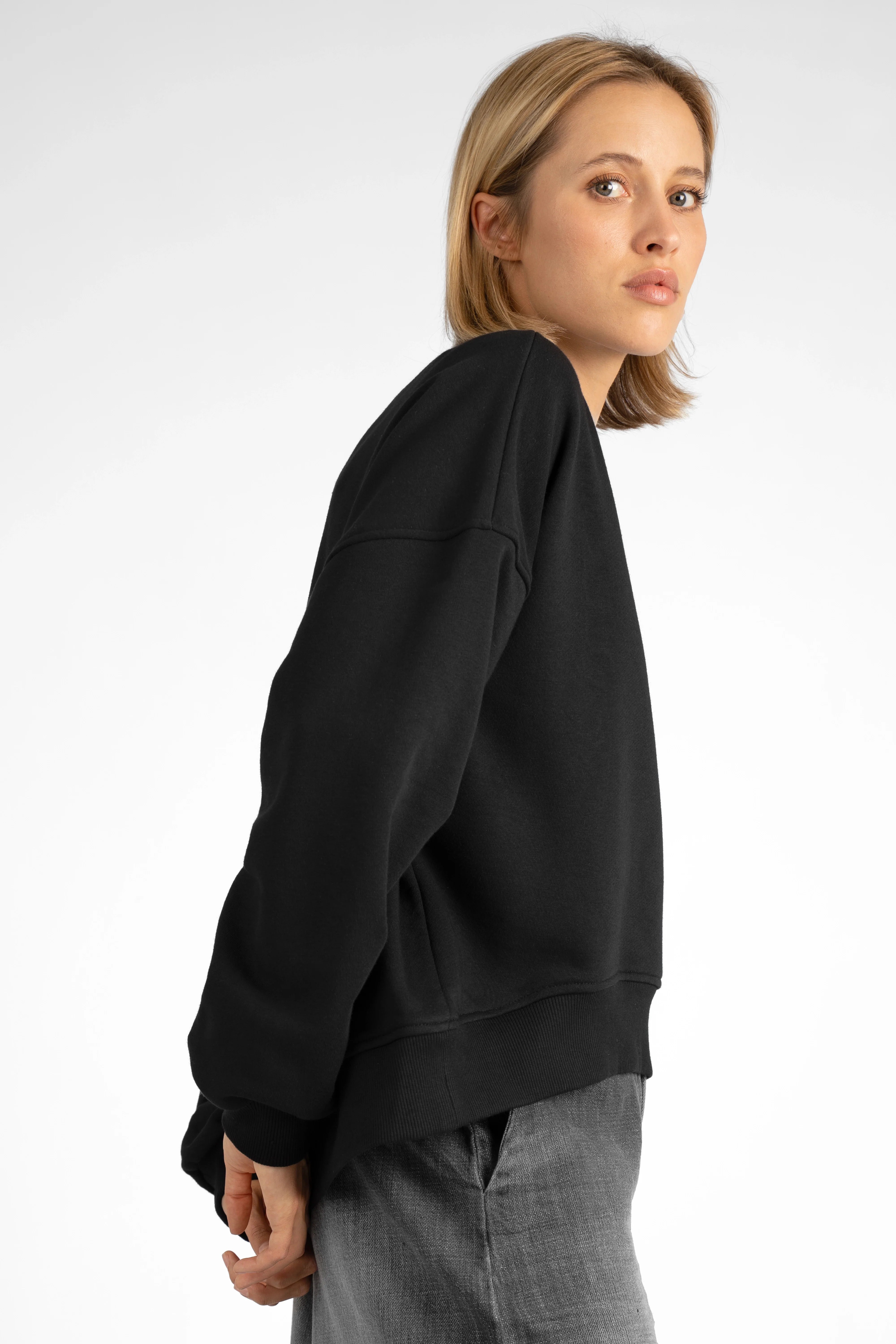 Woman wearing black SEREA Sweater mit V-Ausschnitt with relaxed fit and ribbed cuffs, side view