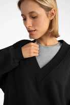 Woman wearing black SEREA Sweater mit V-Ausschnitt with deep V-neck, ribbed cuffs, and relaxed fit.