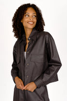 Woman wearing a cropped black shirt-style jacket made from supersoft eco-leather with a Kent collar and large chest pockets