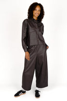 Woman wearing a cropped SOOAE Hemdjacke aus supersoftem Eco-Leder with Kent collar and large chest pockets.