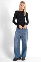 Woman wearing black SUJIN Longsleeve with U-boat neckline and ruched sleeves paired with wide-leg blue jeans