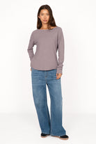 Woman wearing a soft fiammato cotton TEHI Longsleeve with round neckline and extra-long raglan sleeves paired with wide-leg jeans.