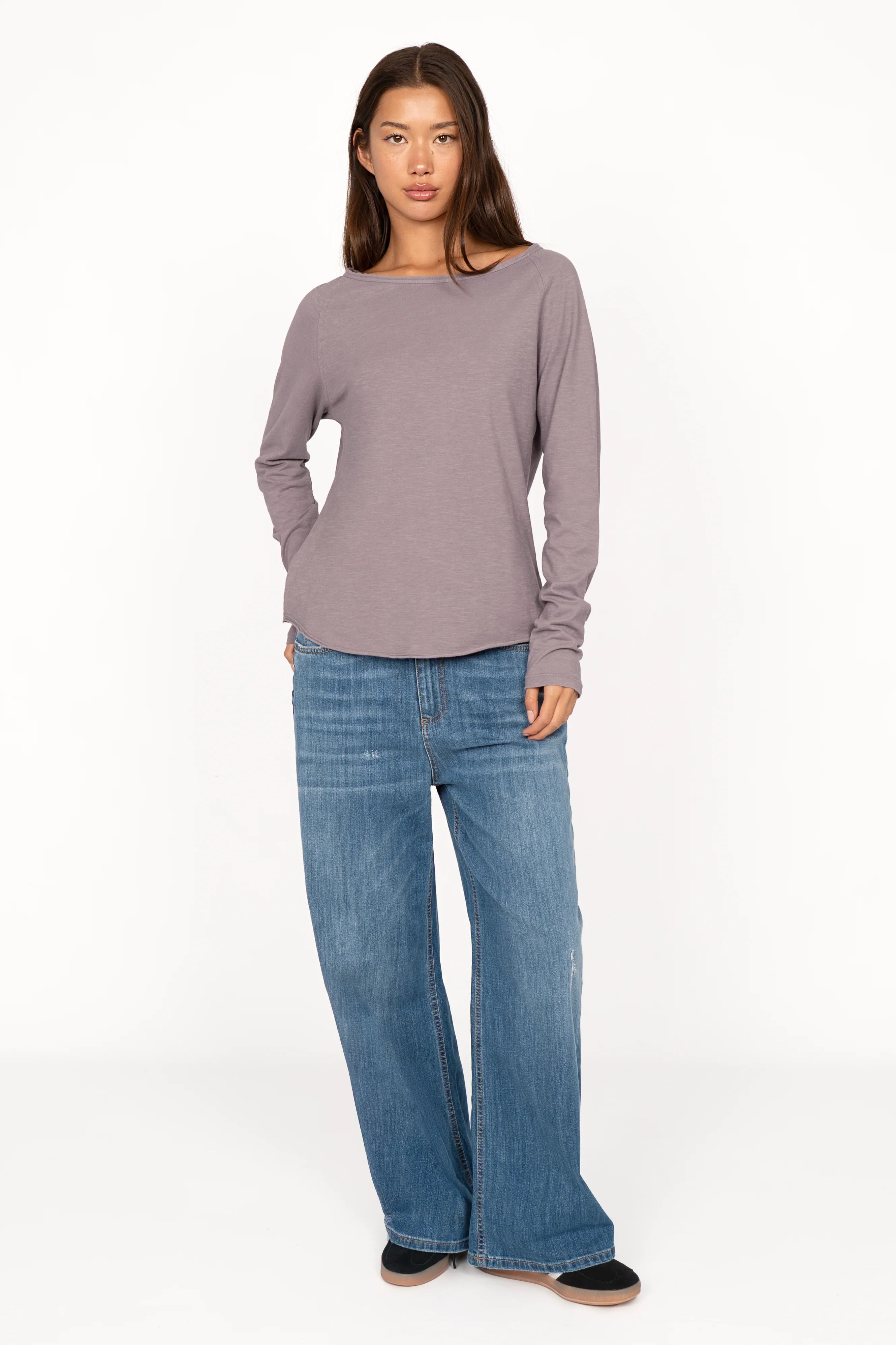 Woman wearing a soft fiammato cotton TEHI Longsleeve with round neckline and extra-long raglan sleeves paired with wide-leg jeans.