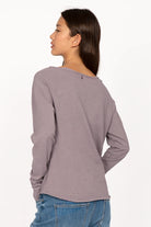 Woman wearing a grey TEHI Longsleeve with extralong raglan sleeves and open edge round neckline, shown from the back.