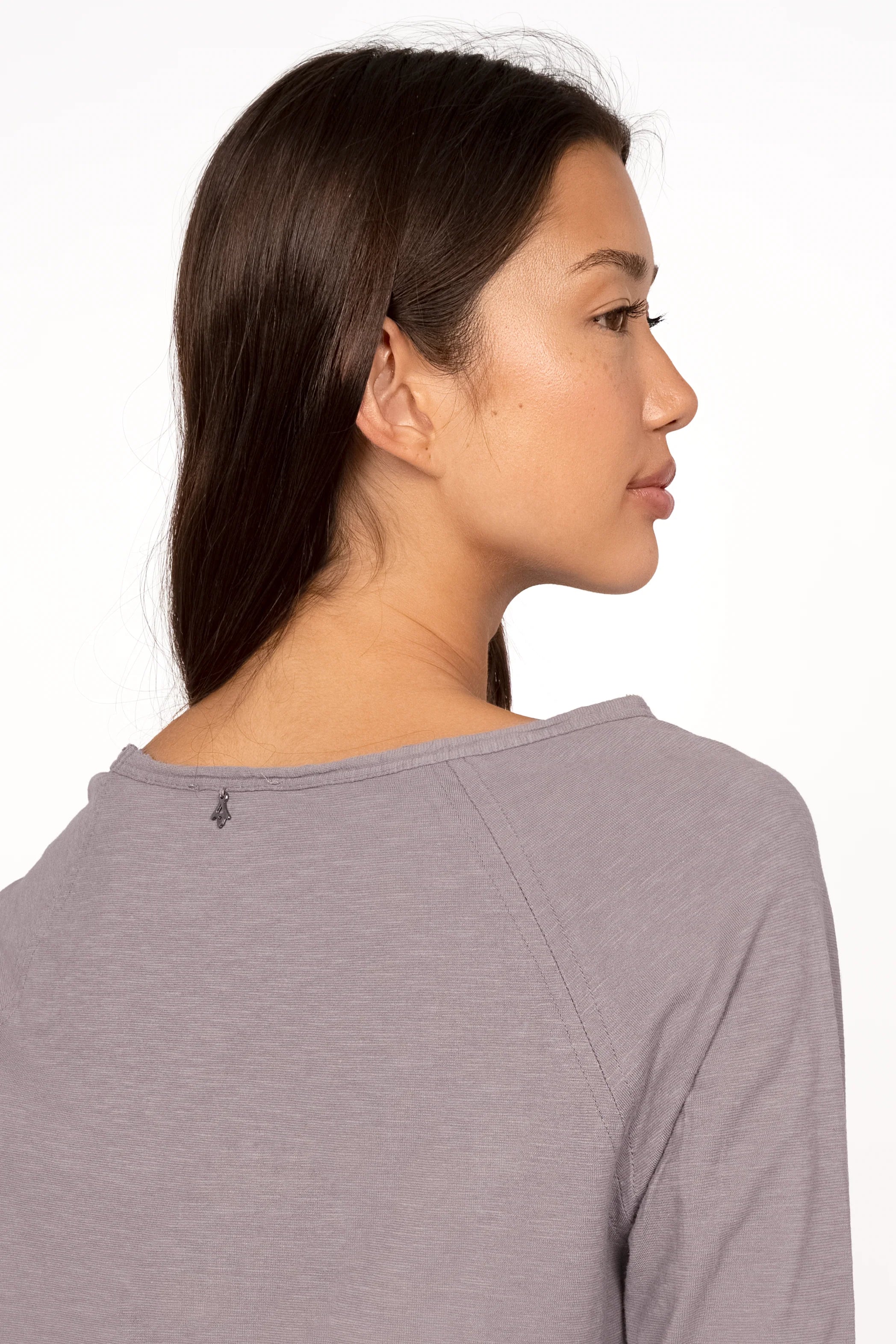 Woman wearing a gray TEHI Longsleeve with open edge round neckline and extra-long raglan sleeves shown from the back.