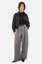 Pantalon gris THIRA à plis avec ceinture, associé à une veste DERA Black et à des bottines noires à bout pointu