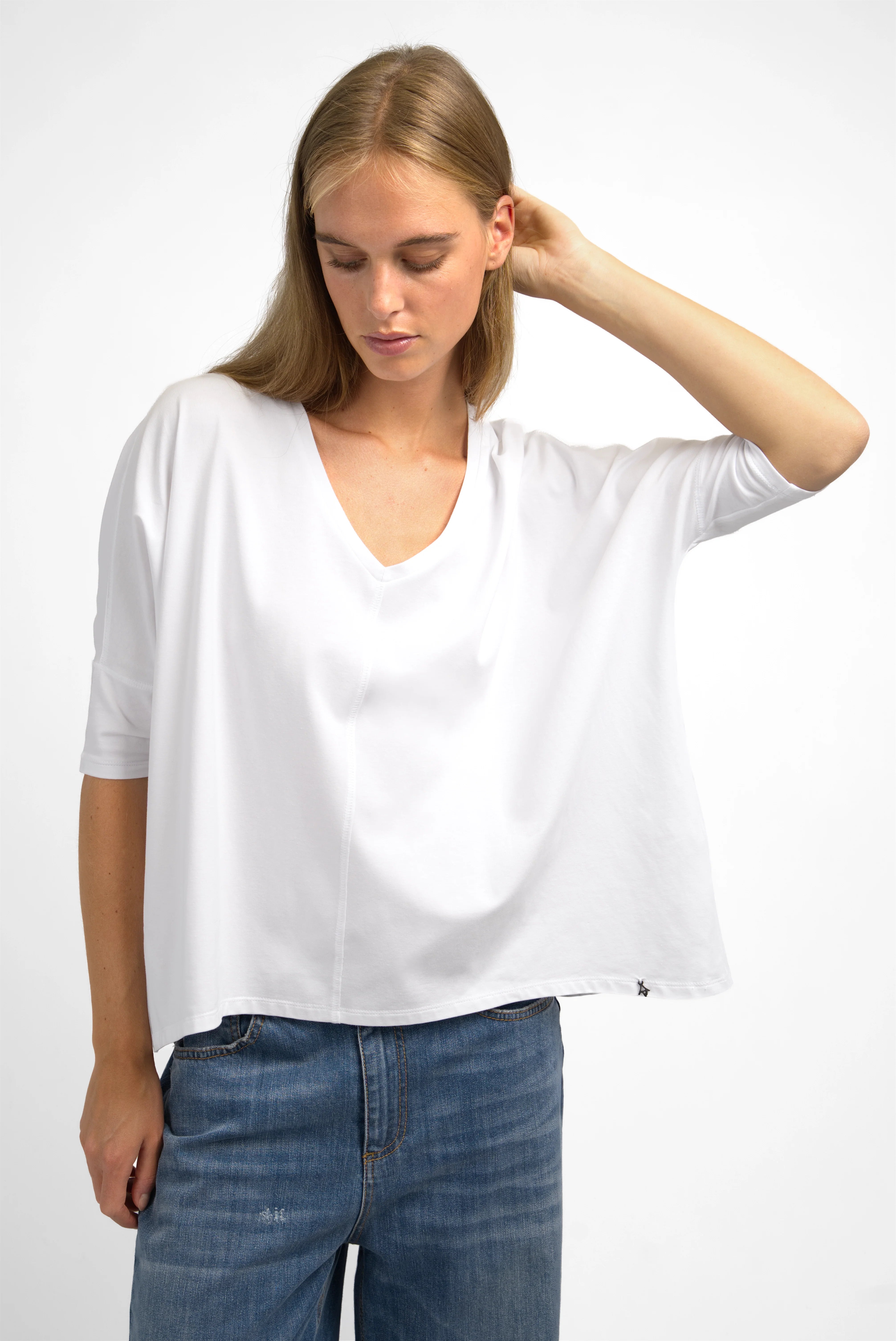Weißes TIDA Blusenshirt mit V-Ausschnitt, kurzer Kastenform und lockerem Schnitt getragen von Model