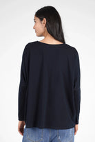 Woman wearing a navy blue TIDA Blusenshirt with long sleeves and a relaxed, boxy fit shown from the back.