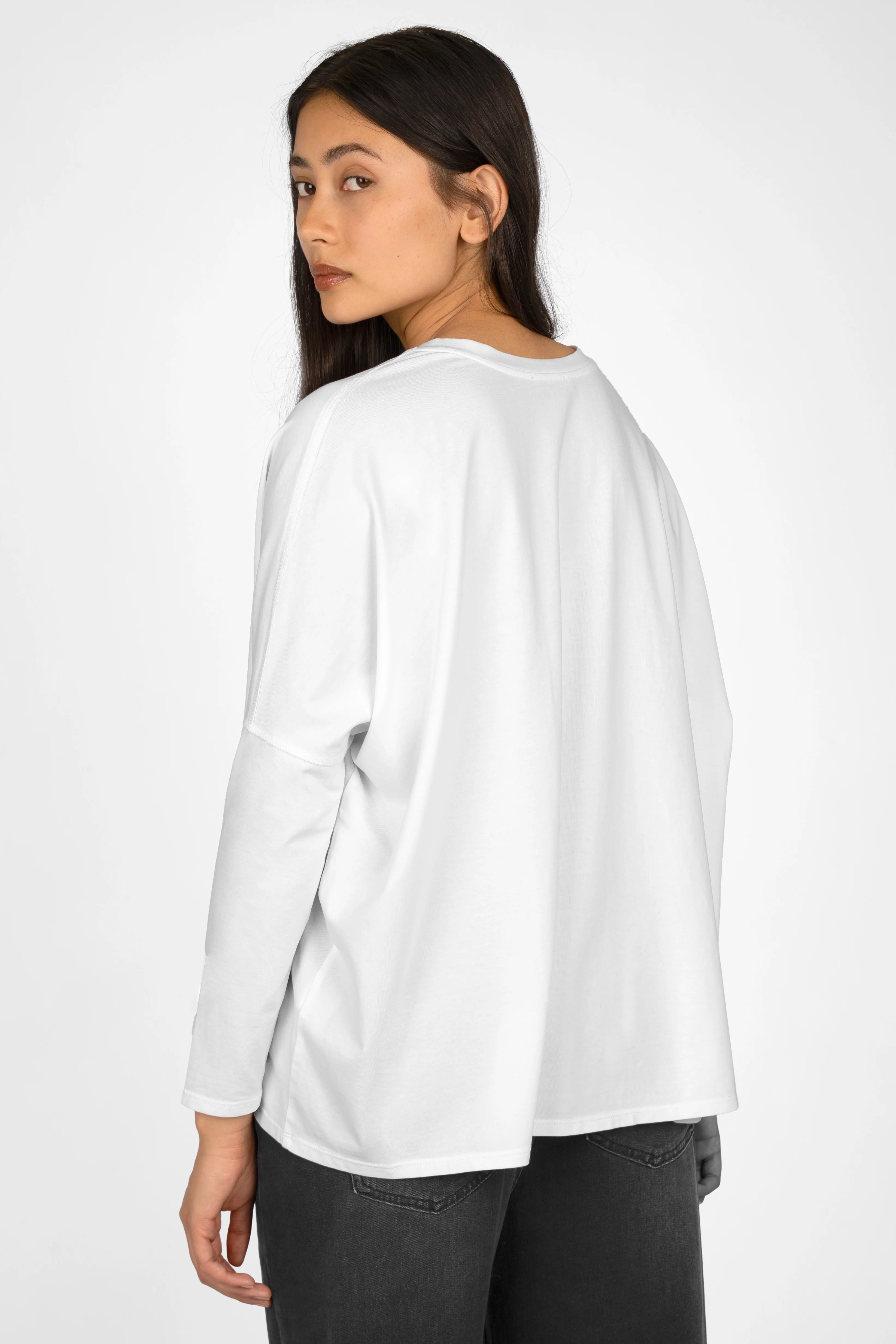 Woman wearing white TIDA Blusenshirt Langarm loose-fit long sleeve shirt with V-neck and longer back hem