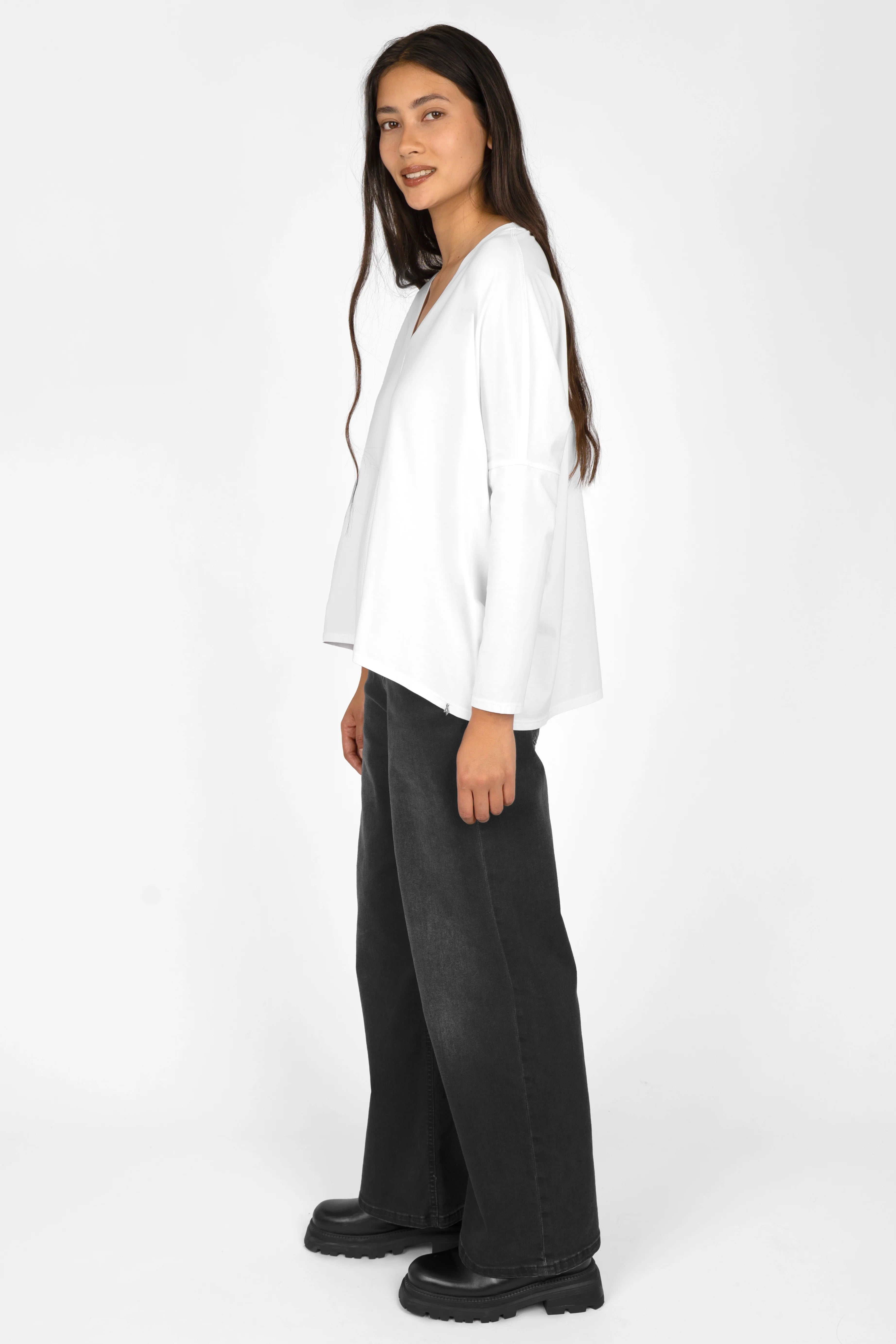 Woman wearing white TIDA Blusenshirt Langarm with V-neck, relaxed fit, and black wide-leg pants.