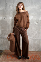 Frau trägt TIMAJ Revive One Shoulder Sweater mit Vintage-Waschung in Mocha und weitem Rundhalsausschnitt lässig über der Schulter