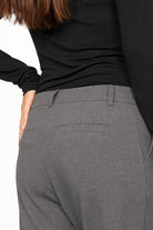Back view of a woman wearing grey TINKE Hose Cropped fit pants with a black long-sleeve top
