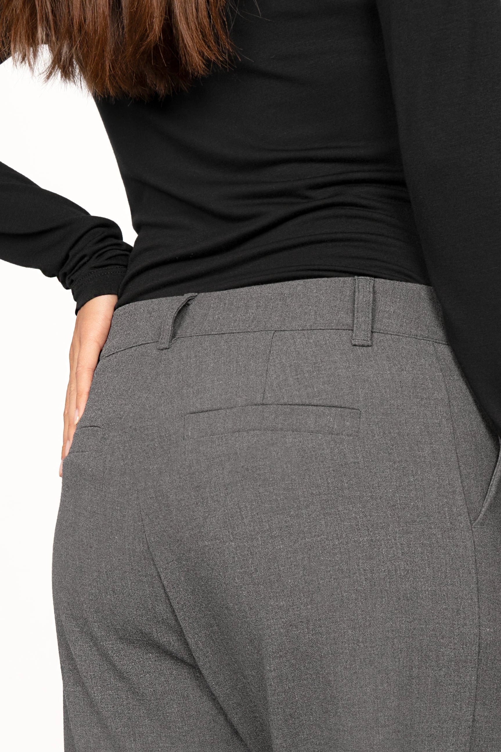 Back view of a woman wearing grey TINKE Hose Cropped fit pants with a black long-sleeve top