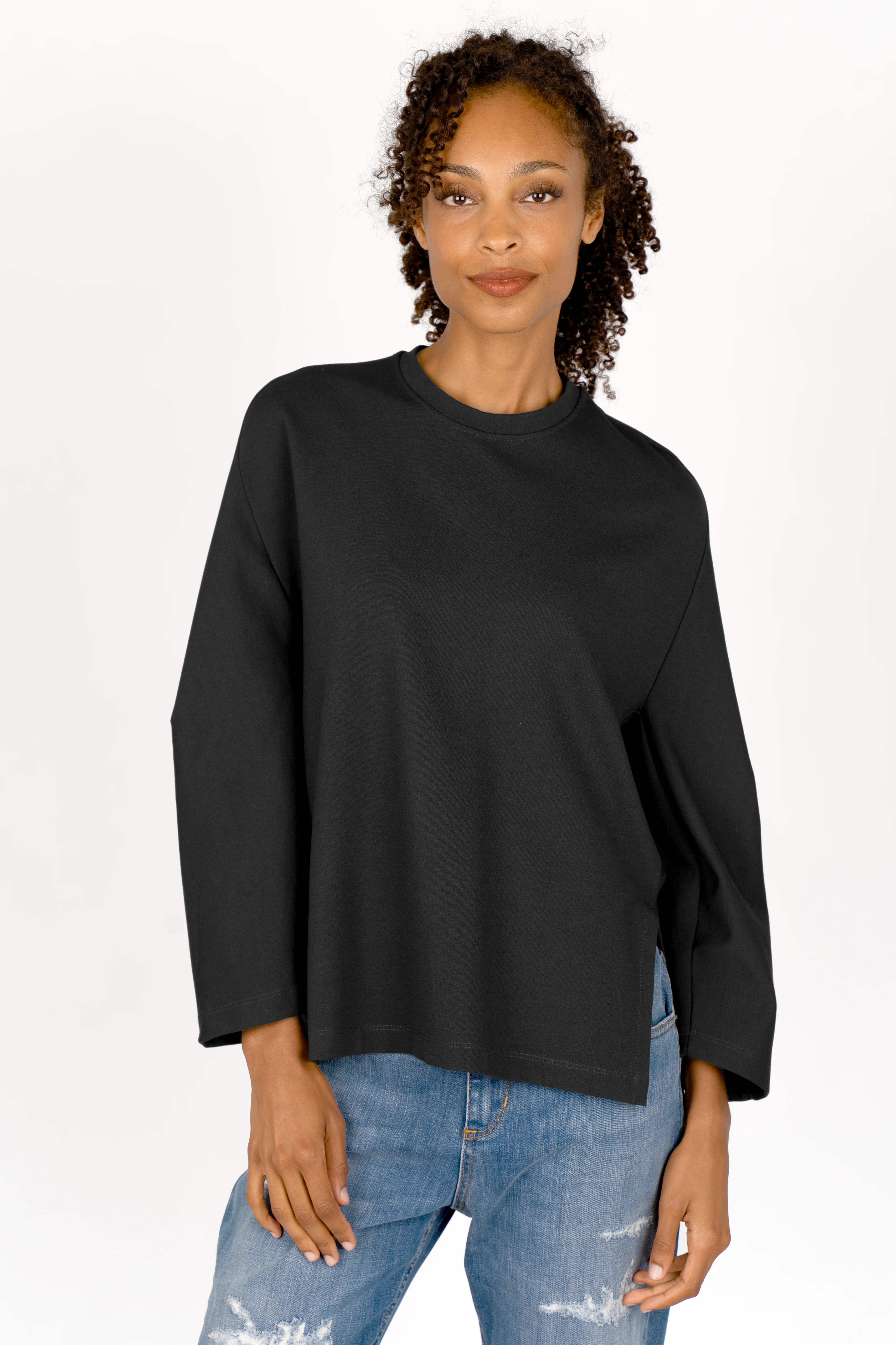 Woman wearing relaxed fit black TOOVE Shirt made of medium-weight interlock jersey with round neckline and extended back hem