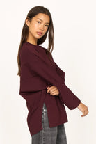 Woman wearing a relaxed fit TOOVE Shirt in dark burgundy interlock-jersey with extended back and high side slits.