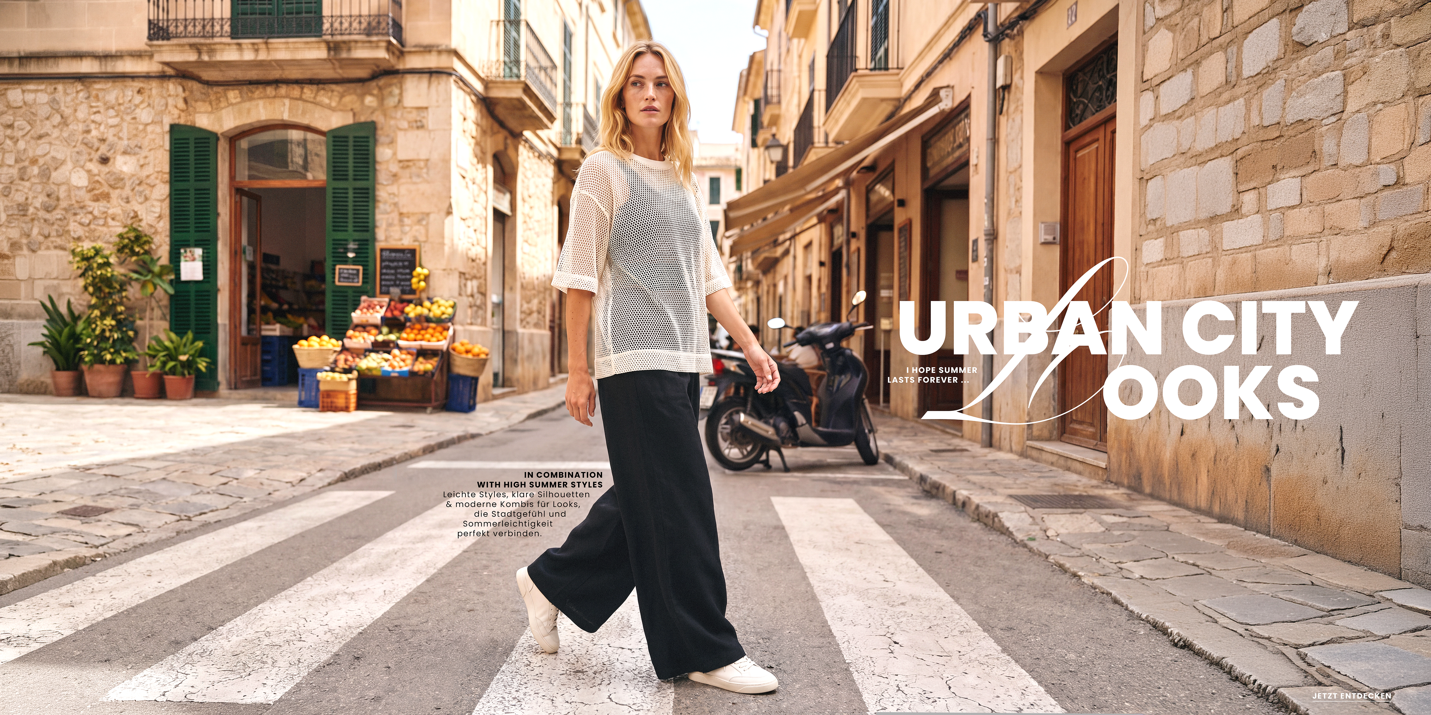 Model im weißen Mesh-Shirt und weiter schwarzer Hose auf Zebrastreifen in urbaner Umgebung – Urban City Look.