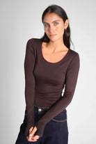 Woman wearing slim fit VALUM Longsleeve with U-boat neckline, extra-long sleeves and thumb holes in dark brown