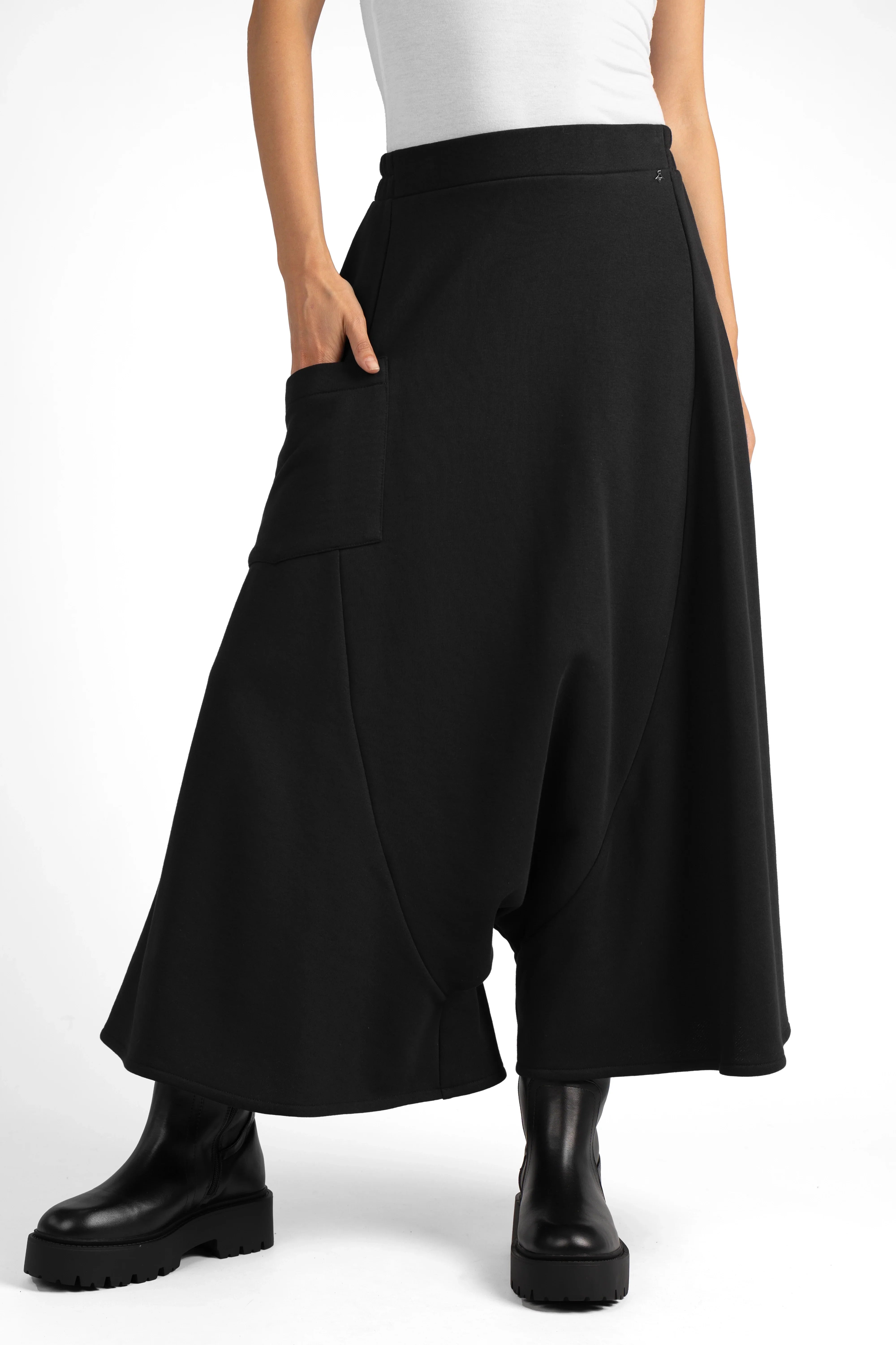 Black radially wide Hosenrock aus Sweat with asymmetrical front pocket and smooth waistband, styled with black boots.