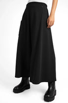 Black radical wide Hosenrock aus Sweat with asymmetrical front pocket and smooth waistband, worn with black boots.